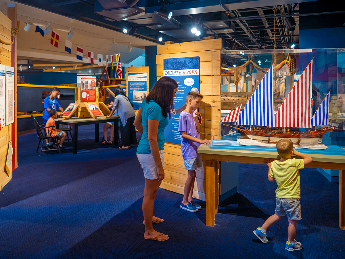A mother and two children look at a model ship displayed in a glass case at the Independence Seaport Museum in Philadelphia.