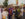 Eight people smile and pose for a photo together while attending the ODUNDE Festival in Philadelphia. Four wear straw hats and most wear colorful patterned clothing.