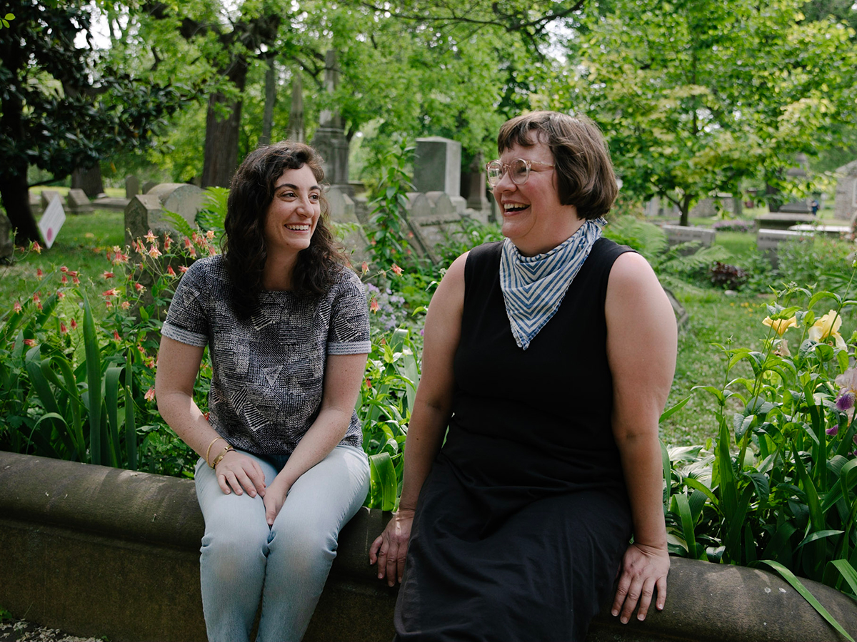 Two people sit on a concrete wall in front of the Grave Gardens at The Woodlands Cemetery and Mansion.