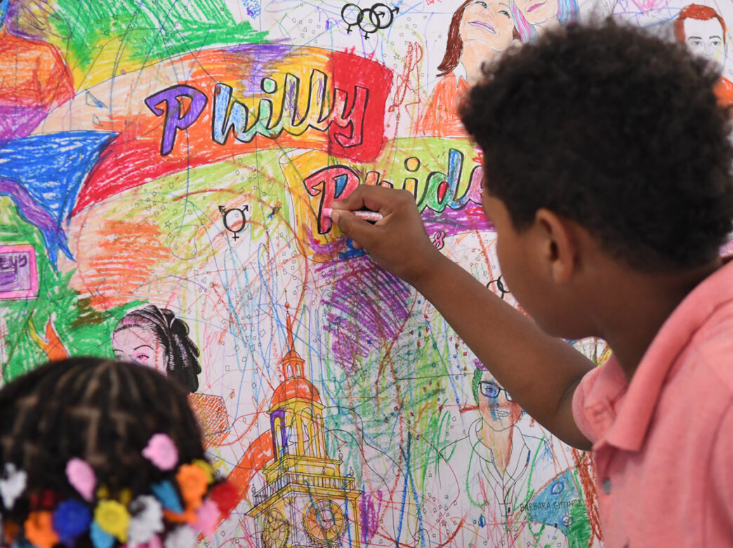 Deux enfants utilisent des crayons pour colorier une bannière de la fierté du Philly au Please Touch Museum à Philadelphie.