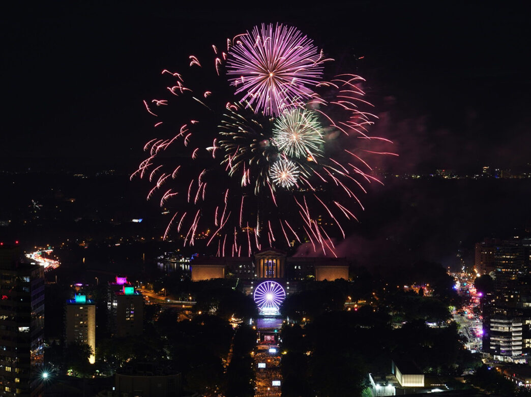 Des feux d'artifice roses, rouges et verts éclatent au-dessus du Philadelphia Museum of Art et du Benjamin Franklin Parkway pendant le spectacle pyrotechnique Wawa Welcome America.