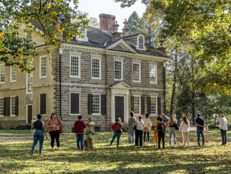 Group of people stand outside on the lawn in front of the Carriage House at Cliveden.
