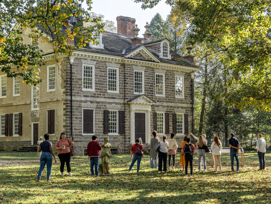 Group of people stand outside on the lawn in front of the Carriage House at Cliveden.