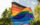 A Pride flag sways in the breeze in front of leafy trees in Philadelphia