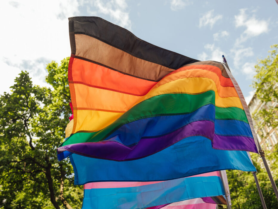 A Pride flag sways in the breeze in front of leafy trees in Philadelphia