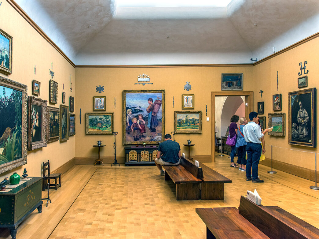 Un pequeño grupo de visitantes contempla las obras de arte que adornan las paredes del Barnes Foundation.