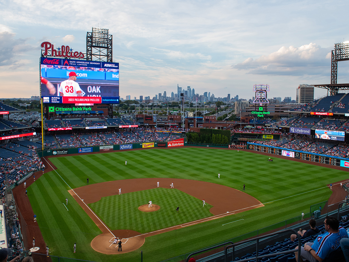 A view of a Citizens Bank Park overlooking the baseball field, people in the stadium and Philadelphia's skyline in the distance.