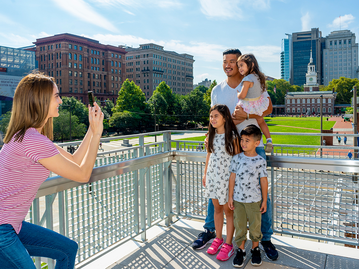 A family poses for a photo on the terrace at Liberty View with Independence Hall in the background.