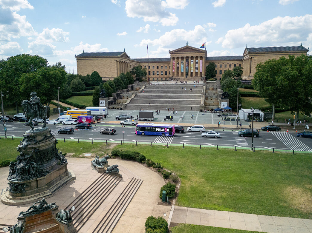 A pink and purple PHLASH bus passes the Philadelphia Museum of Art.