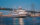 A white three-level yacht cruises along the Delaware River at night with the Benjamin Franklin Bridge in the background.