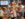 People wearing Lederhosen raise liter beer glasses into the air while attending an Oktoberfest event.