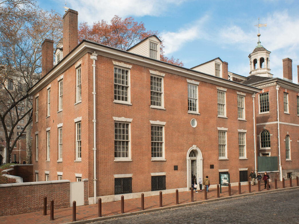 The exterior of a red brick building with a white cupola and dormers.