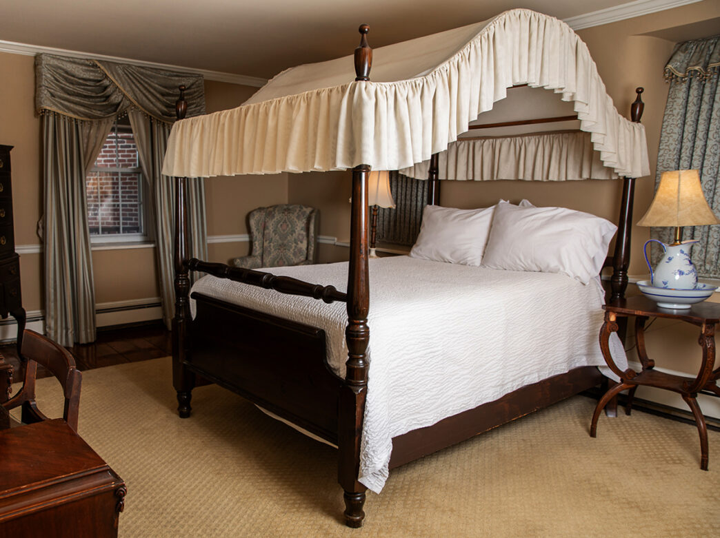 Una habitación de hotel decorada con muebles de época y un dosel de cama.