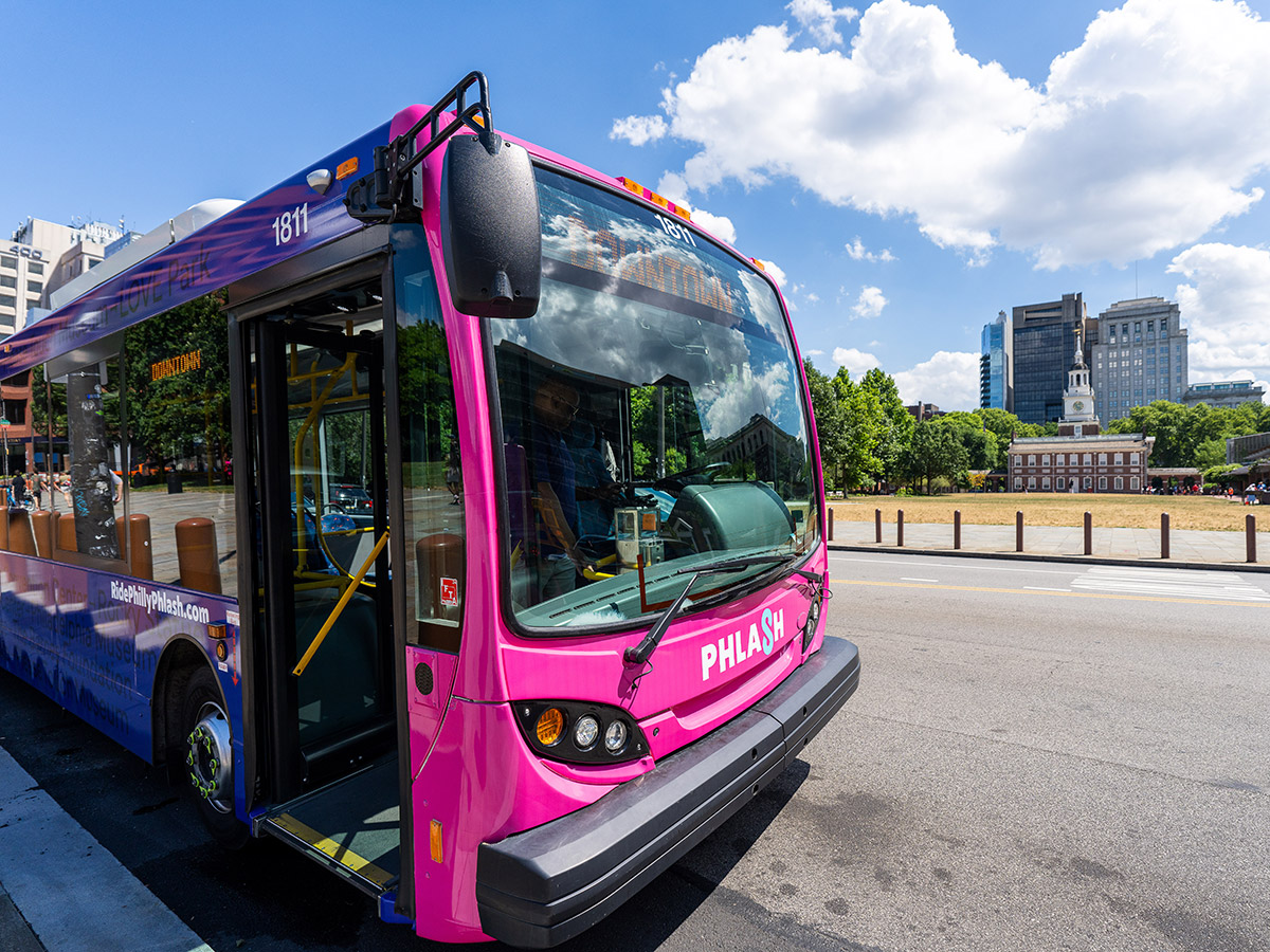 The pink and purple Philly PHLASH bus parked in front of Independence Hall