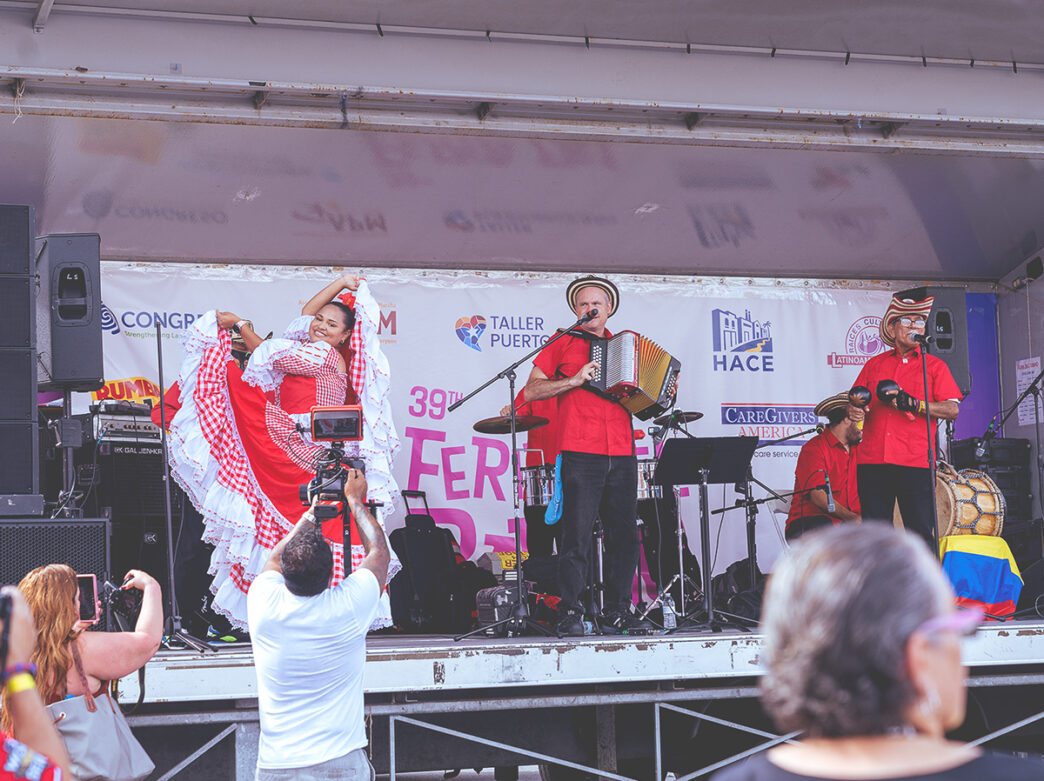 A dancer and musicians wearing red perform on stage at the La Feria del Barrio festival in Philadelphia.