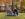 Two women sit in the grass together drinking coffee and laughing in Rittenhouse Square on a fall day.
