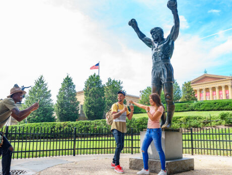 Two people pose in a boxing stance in front of the bronze Rocky Statue at the Philadelphia Museum of Art.