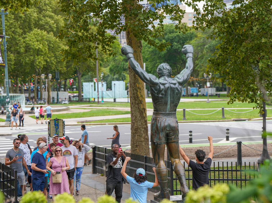 People stand in line and pose for a photo with the bronze Rocky statue in Philadelphia.