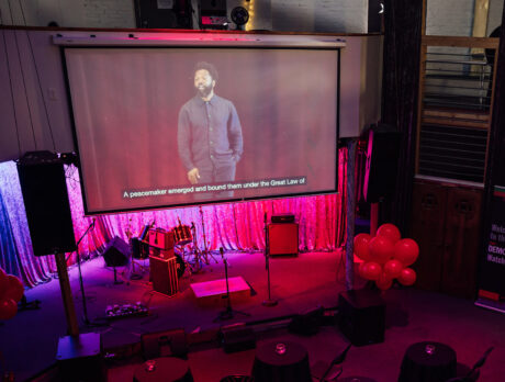 A screen shows the TED Democracy Talk in Philadelphia at a community watch party