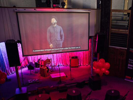 Una pantalla muestra la charla TED Democracy Talk en Filadelfia en una fiesta de observación comunitaria