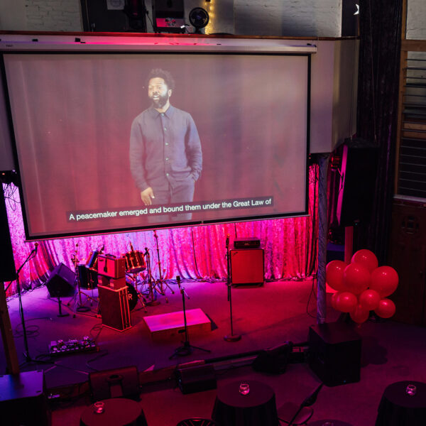 A screen shows the TED Democracy Talk in Philadelphia at a community watch party