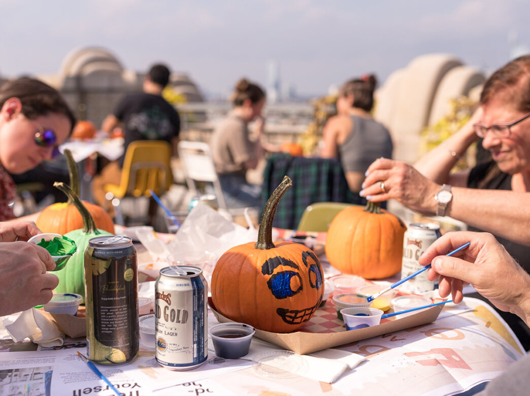 People sit at tables covered with newspaper while they paint faces on pumpkins at Boktober Fest at the Bok.