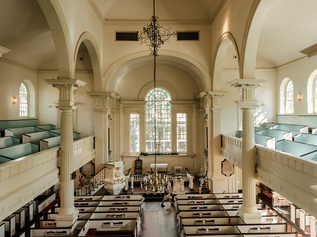 An interior view of Christ Church in Philadelphia. The image is taken from the balcony and looks down on the pews and alter.
