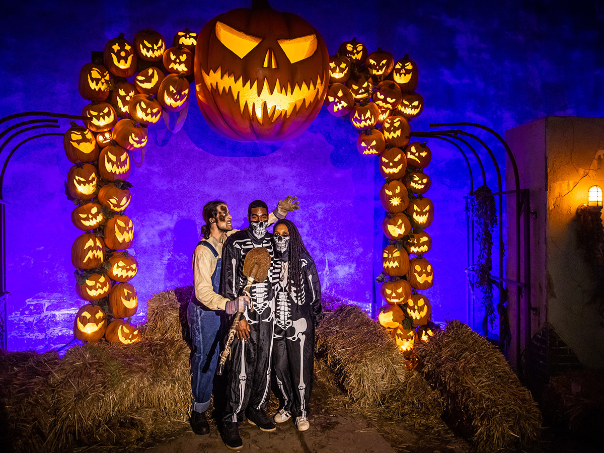 A costumed couple (dressed as skeletons) poses for a picture with an undead farmer at Eastern State Penitentiary.