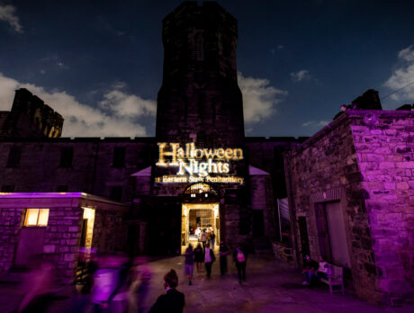 The front gates of Eastern State Penitentiary are illuminated in lights that read "Halloween Nights at Eastern State Penitentiary."