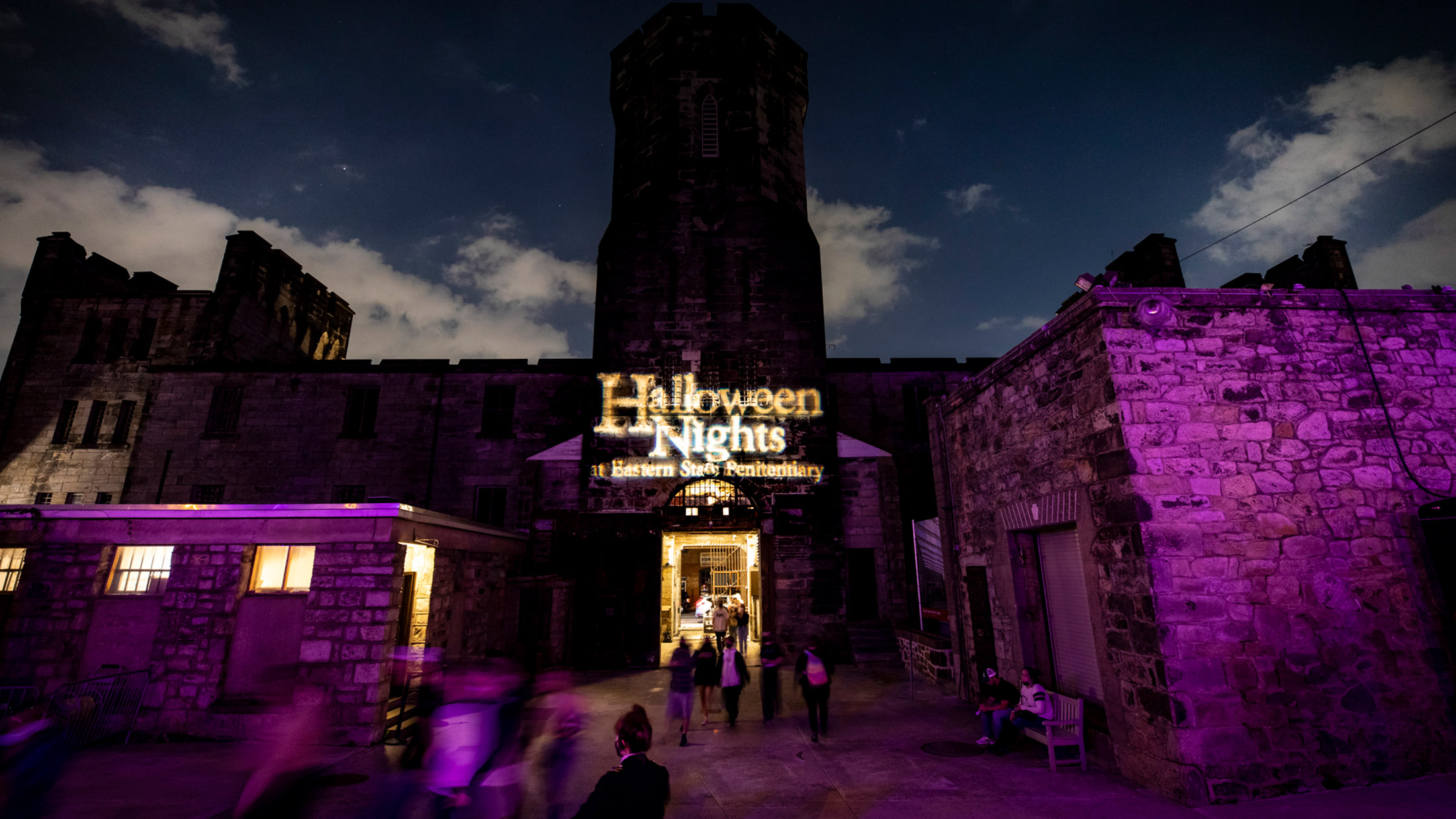 The front gates of Eastern State Penitentiary are illuminated in lights that read "Halloween Nights at Eastern State Penitentiary."