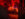 Awash in red light, a scared, screaming visitor is cornered by a haunted house character.