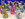 Hand-painted clay dog figurines are displayed in front of a blue background. The figurines are painted with a variety of colorful paints.