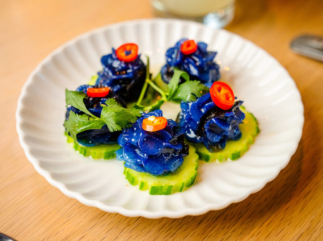Five blue, flower-shaped dumplings, Shaw Muang, are displayed on a white plate at Kalaya.