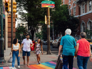 Mensen steken een straat over in Philadelphia met een regenboogzebrapad.