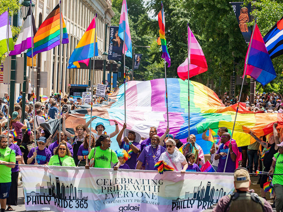 Los manifestantes del desfile, vestidos con camisetas de color verde lima y morado, llevan una bandera del orgullo arcoíris de 400 pies de largo por el centro de la ciudad.