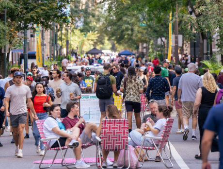 People sit in lawn chairs and walk along a car-free street while enjoying Rittenhouse Square Open Streets: West Walnut.