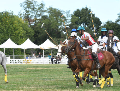 Six players wearing polo uniforms and helmets ride their horses during a match.