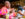 A person wearing a pink and orange dress holds up a forkful of meat while dining at Zahav.