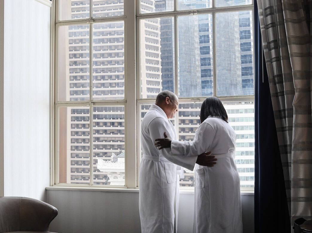 A couple dressed in white robes take in the city views from their room in The Notary.