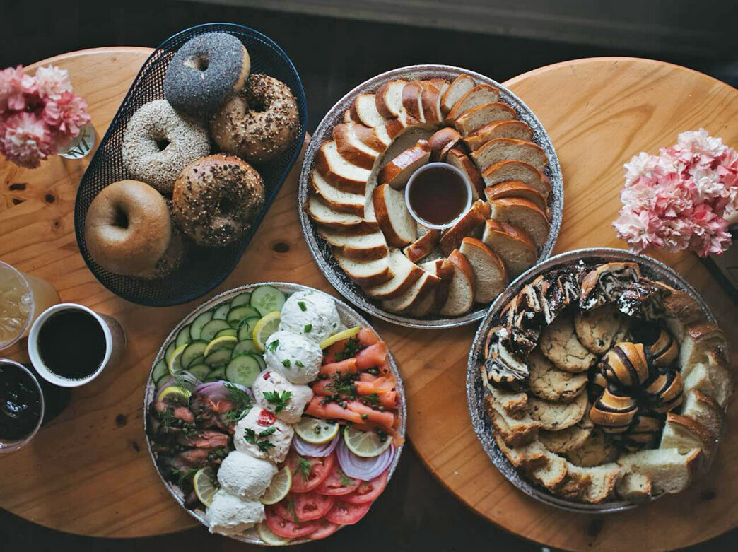 Assorted pastries, breads, bagels and lox are displayed on wooden tables at Essen Bakery.