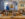 Voltaire Blain, owner of Style by Blain, wears a blue suit and stands behind a table with a display of shoes.
