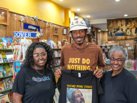 Three people post for a photograph and smile at the camera at Hakim's Bookstore in Philadelphia