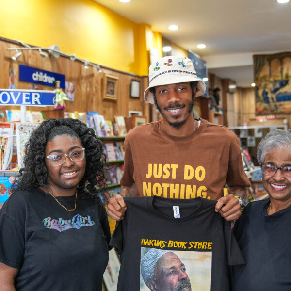 Trois personnes se postent pour une photo et sourient à l'appareil dans la librairie Hakim à Philadelphie.
