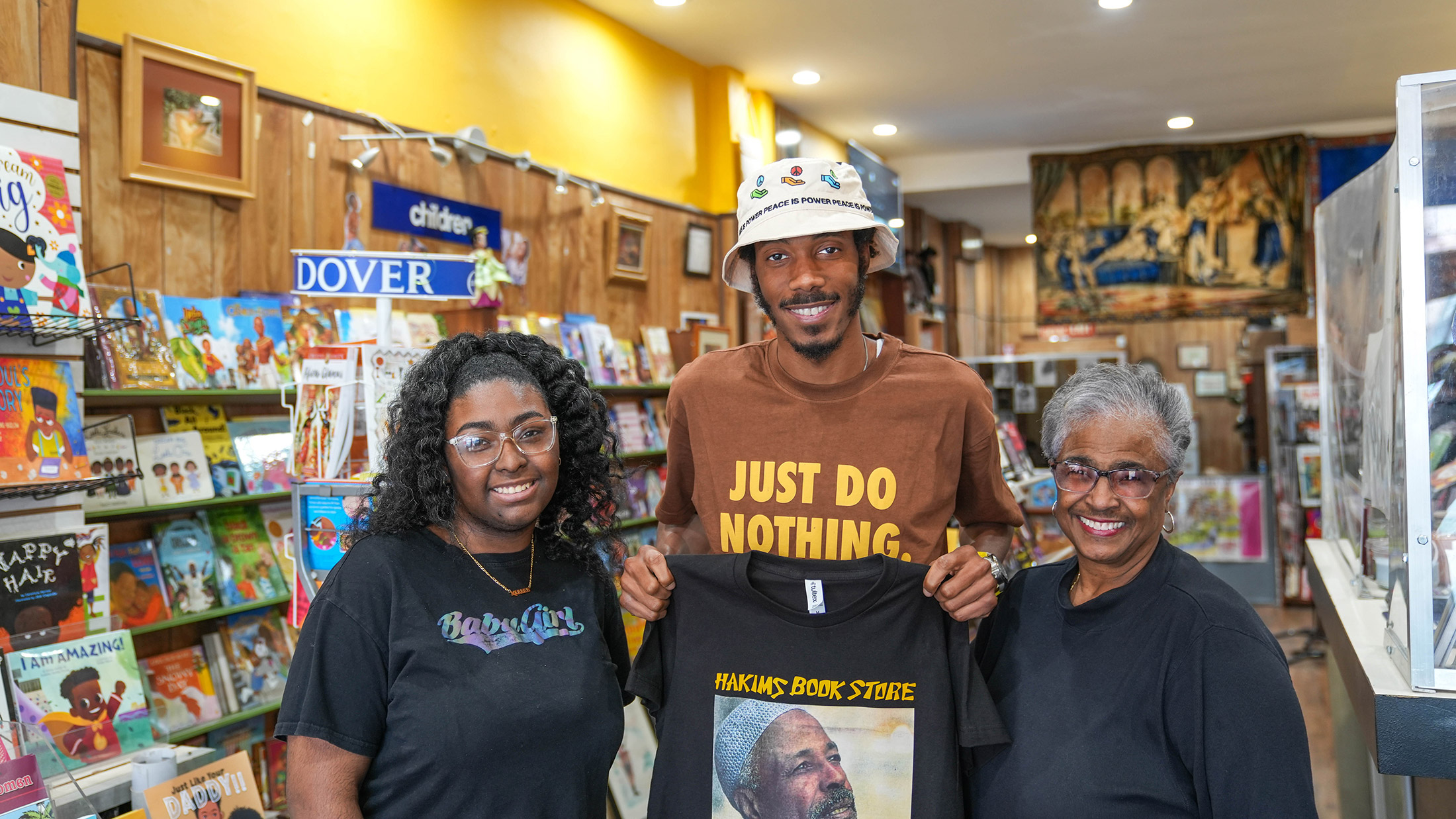 Three people post for a photograph and smile at the camera at Hakim's Bookstore in Philadelphia