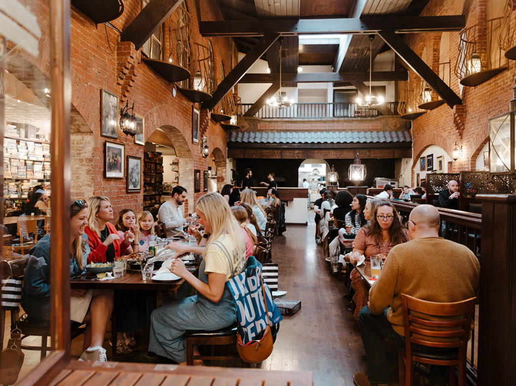 People sit at tables to eat and play games at Queen and Rook Game Cafe.