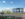 A rendering of a gray industrial building on the new The Bellwether District industrial campus. Cars are parked in a parking lot in front of the building.