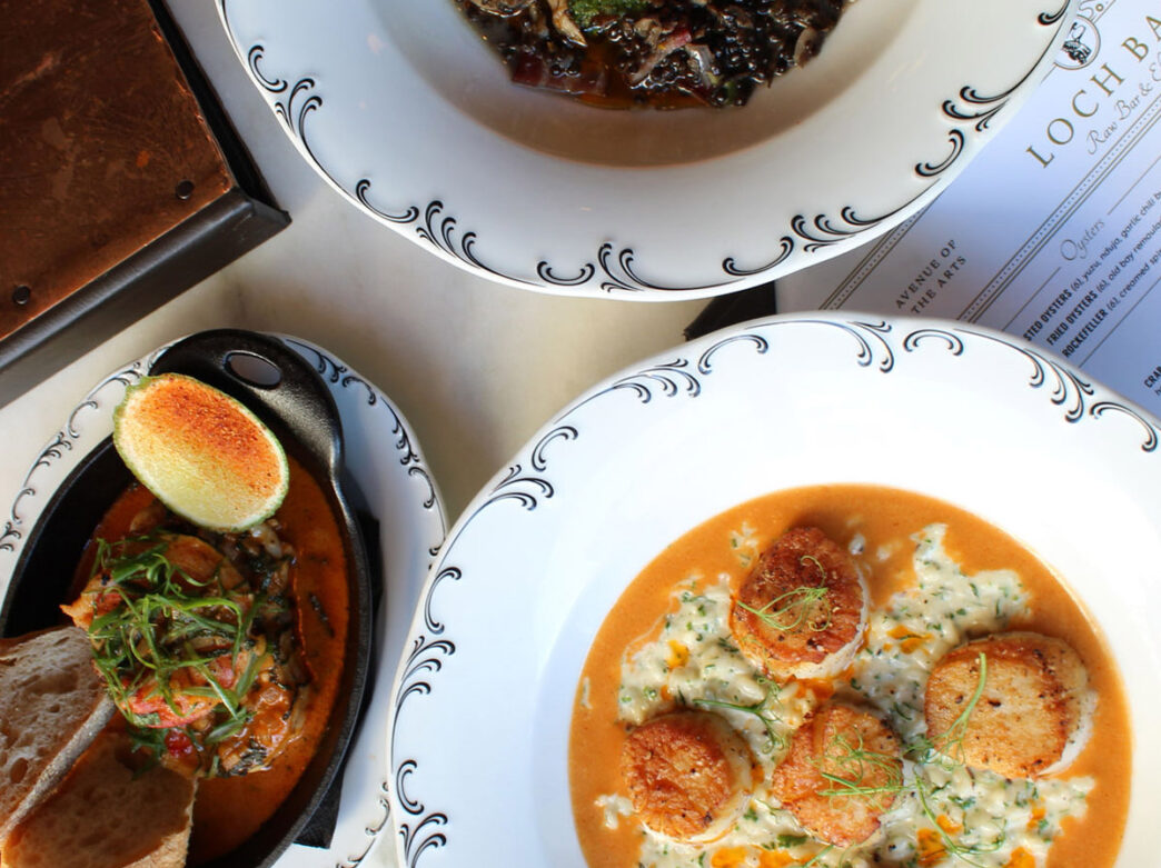 A spread of several seafood dishes on a table covered with a white tablecloth.