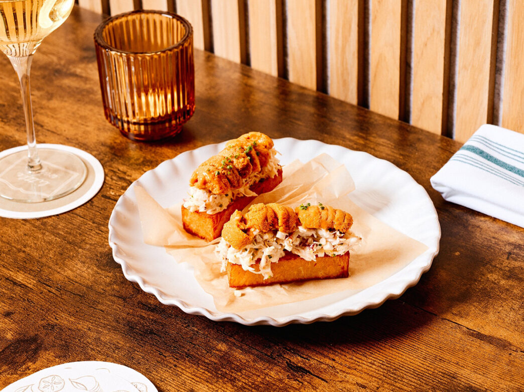 Two hash browns loaded with crab are displayed on a white plate at Little Water.