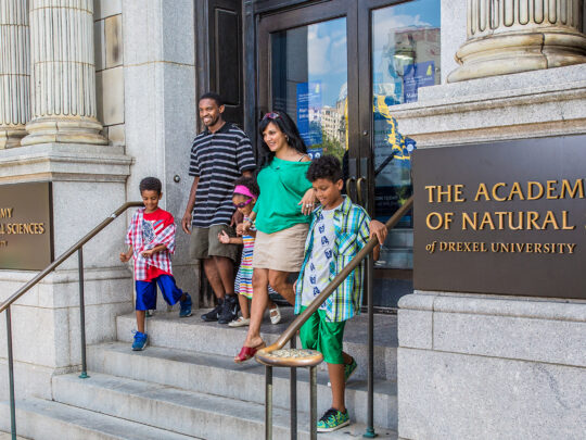 A family of five walks down the granite steps out of The Academy of the Natural Sciences of Drexel University.