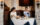 Two women sit in a corner booth table and dine at Estia. They both have glasses of wine and several dishes with food are on the table. Behind them are tapestries hanging on the wall.